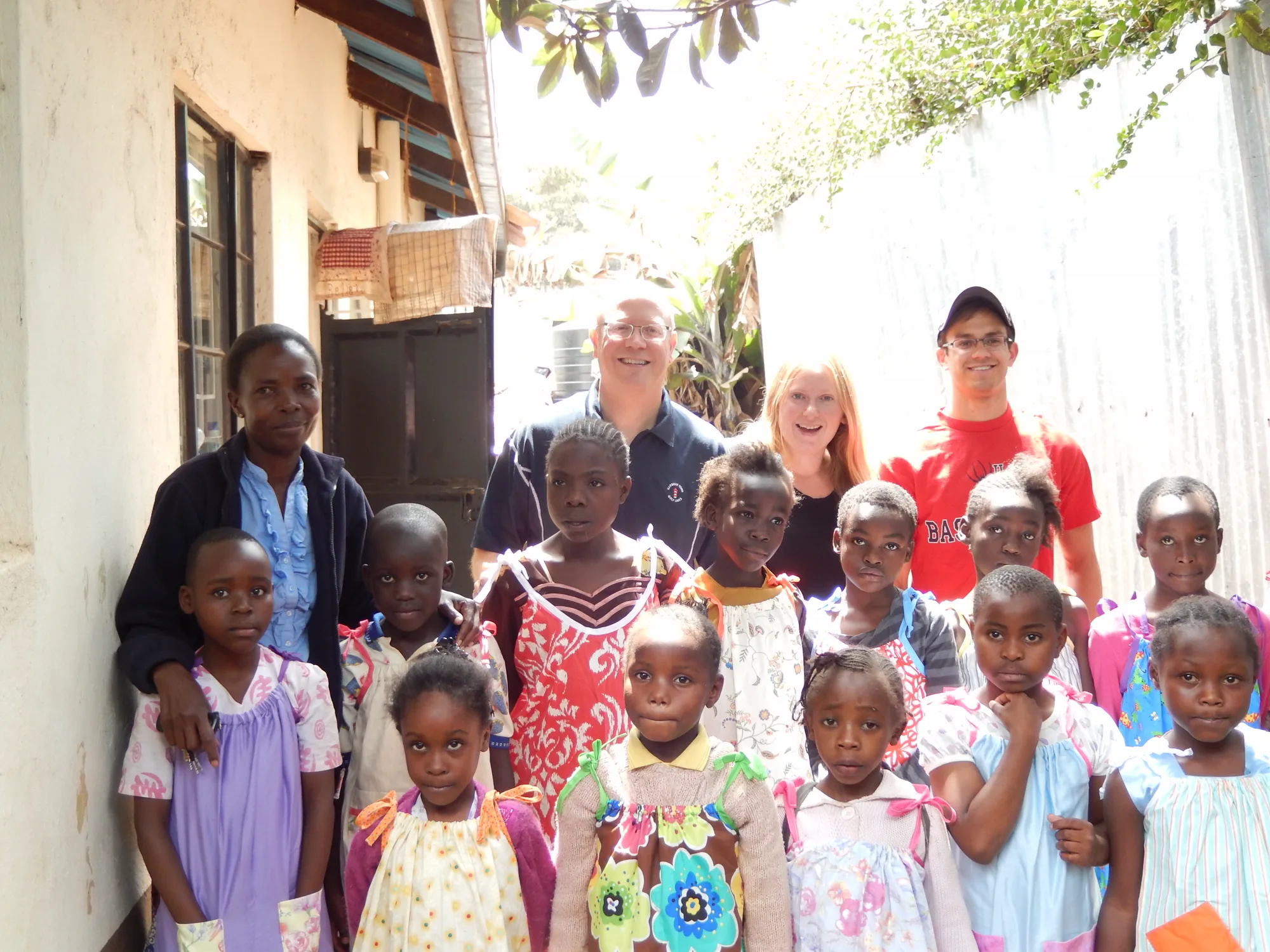 Smiles Bring Hope volunteers with a group of children outside a community building