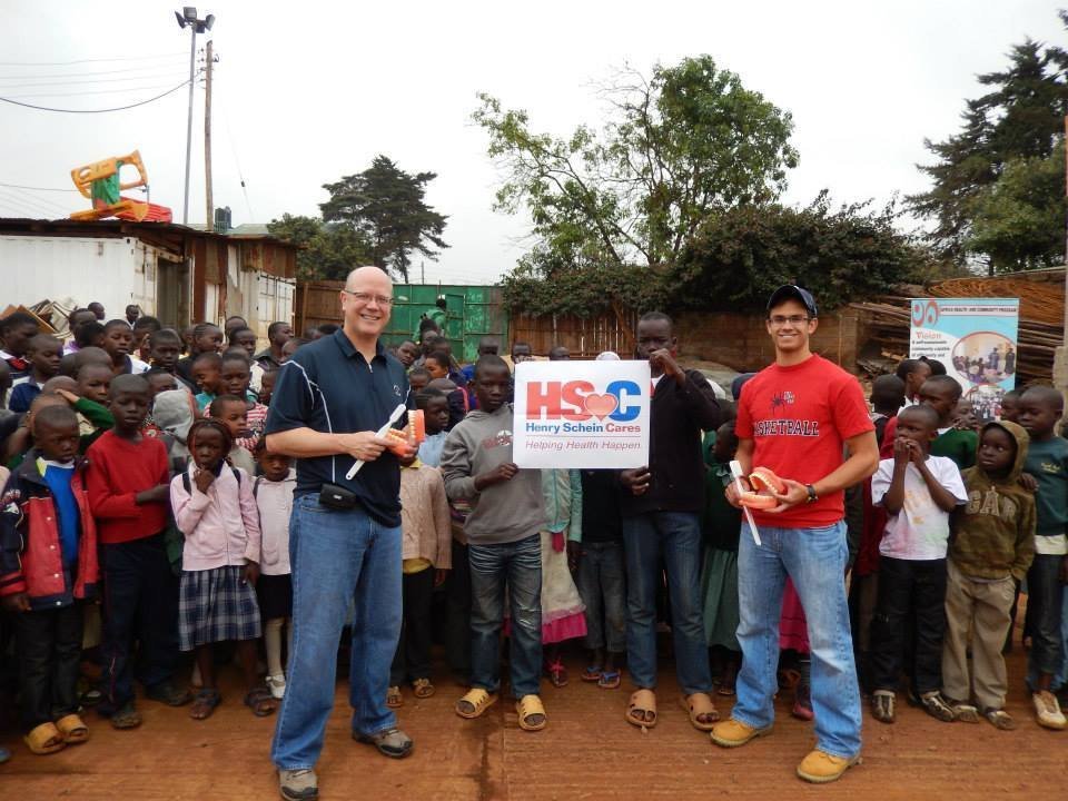 Smiles Bring Hope volunteers holding dental models among a large group of children at an early international mission
