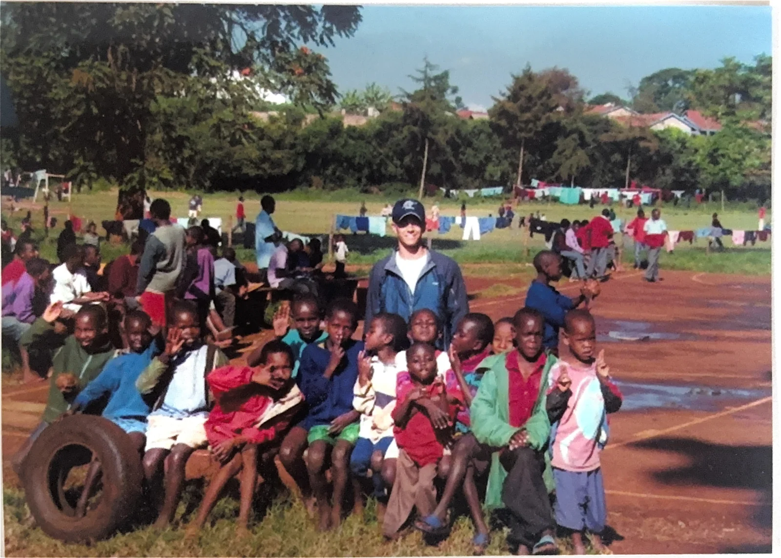 A large group of children gathered with a Smiles Bring Hope volunteer during a community visit in Kenya