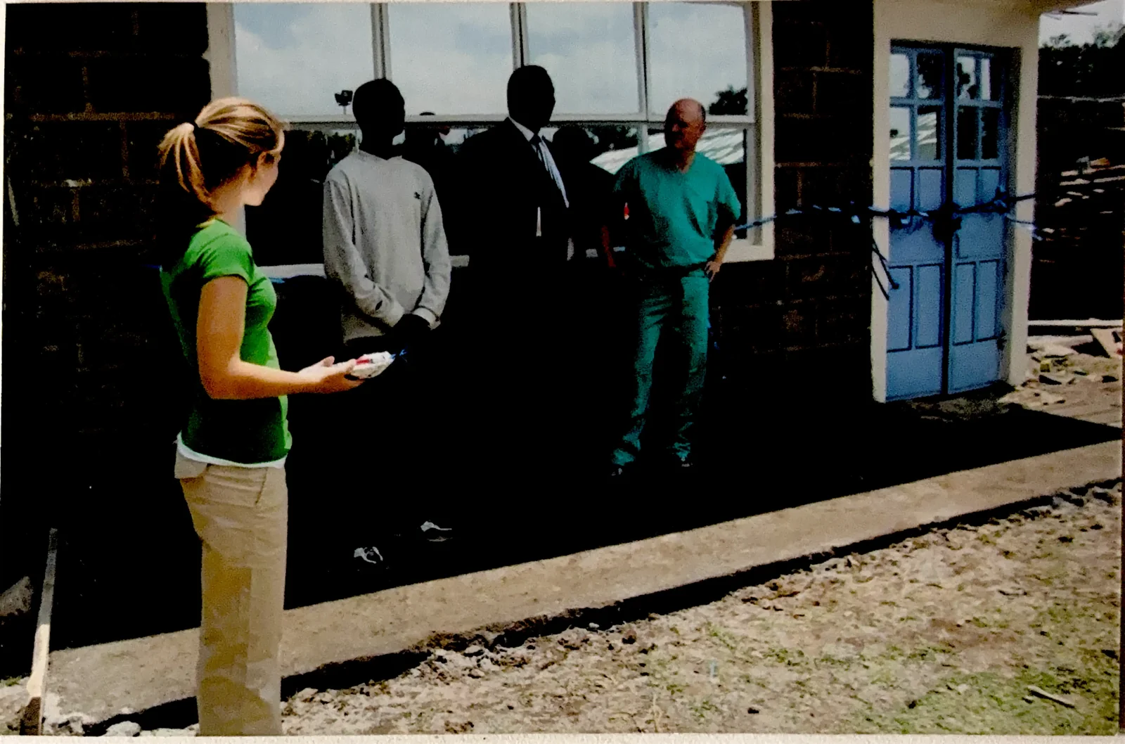 A ribbon-cutting ceremony at the doors of a newly completed clinic in Kenya, with partners and clinicians gathered outside