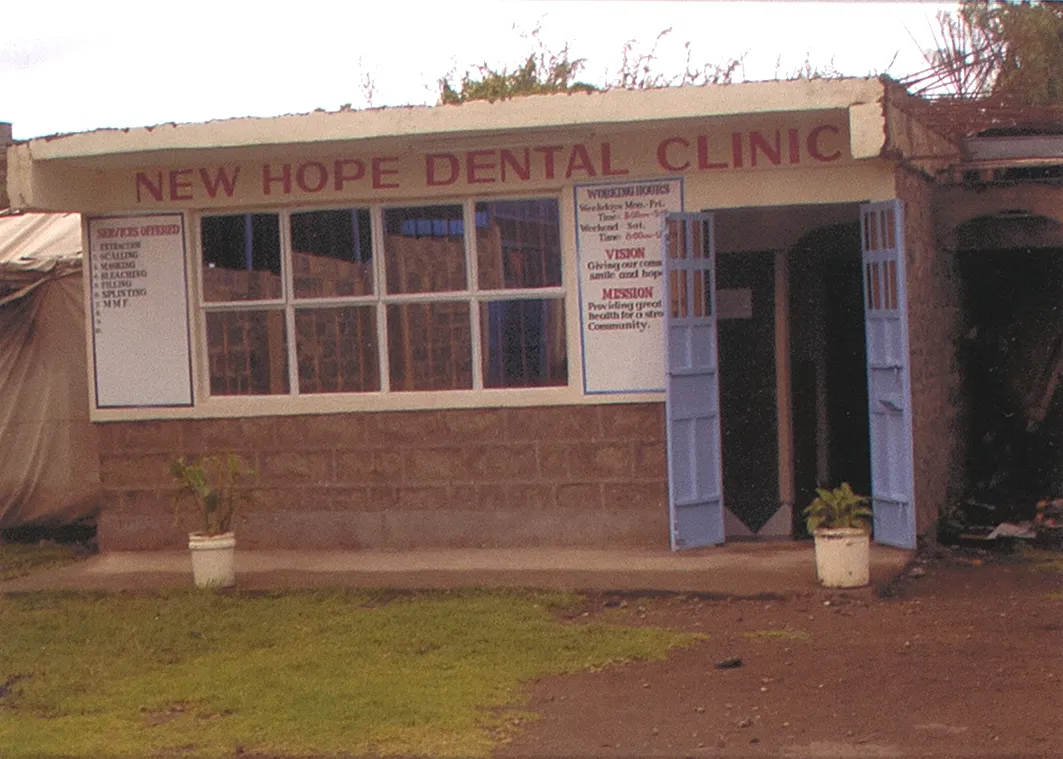 Exterior of the New Hope Dental Clinic in Kenya showing its painted sign and posted opening hours
