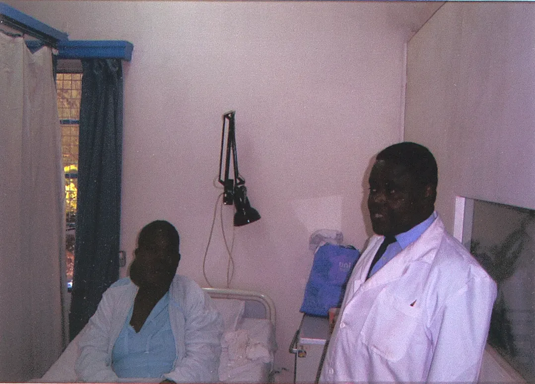 A clinician in a white coat with a patient in a mission clinic examination room